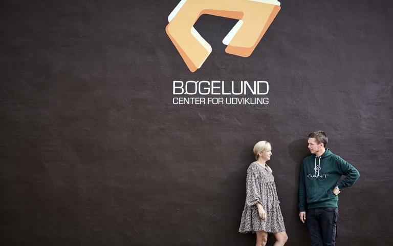 To personer foran mur med logo