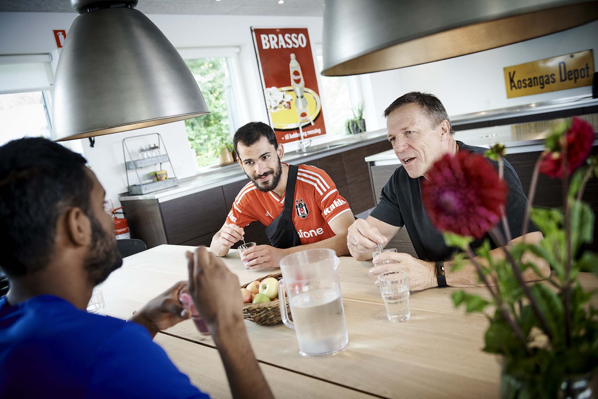 Tre personer omkring køkkenbordet